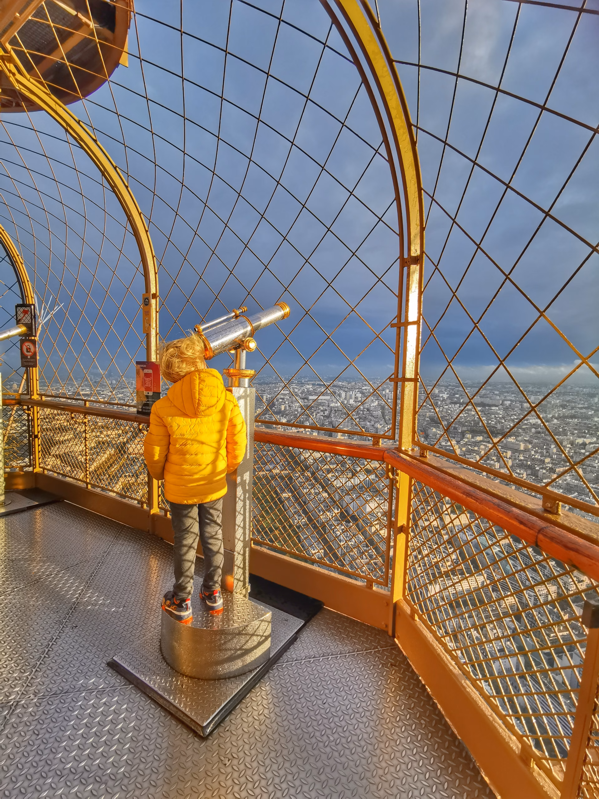 mon fils regarde dans la jumelle la vue de Paris depuis la tour eiffel