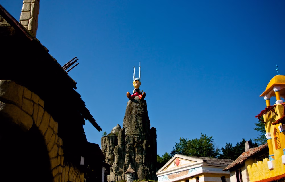 Plongée Dans L'Univers D'Astérix : Guide Complet Du Parc Astérix (Hauts-De-France) 4 Statue d'astérix sur une montagne, ciel bleu.