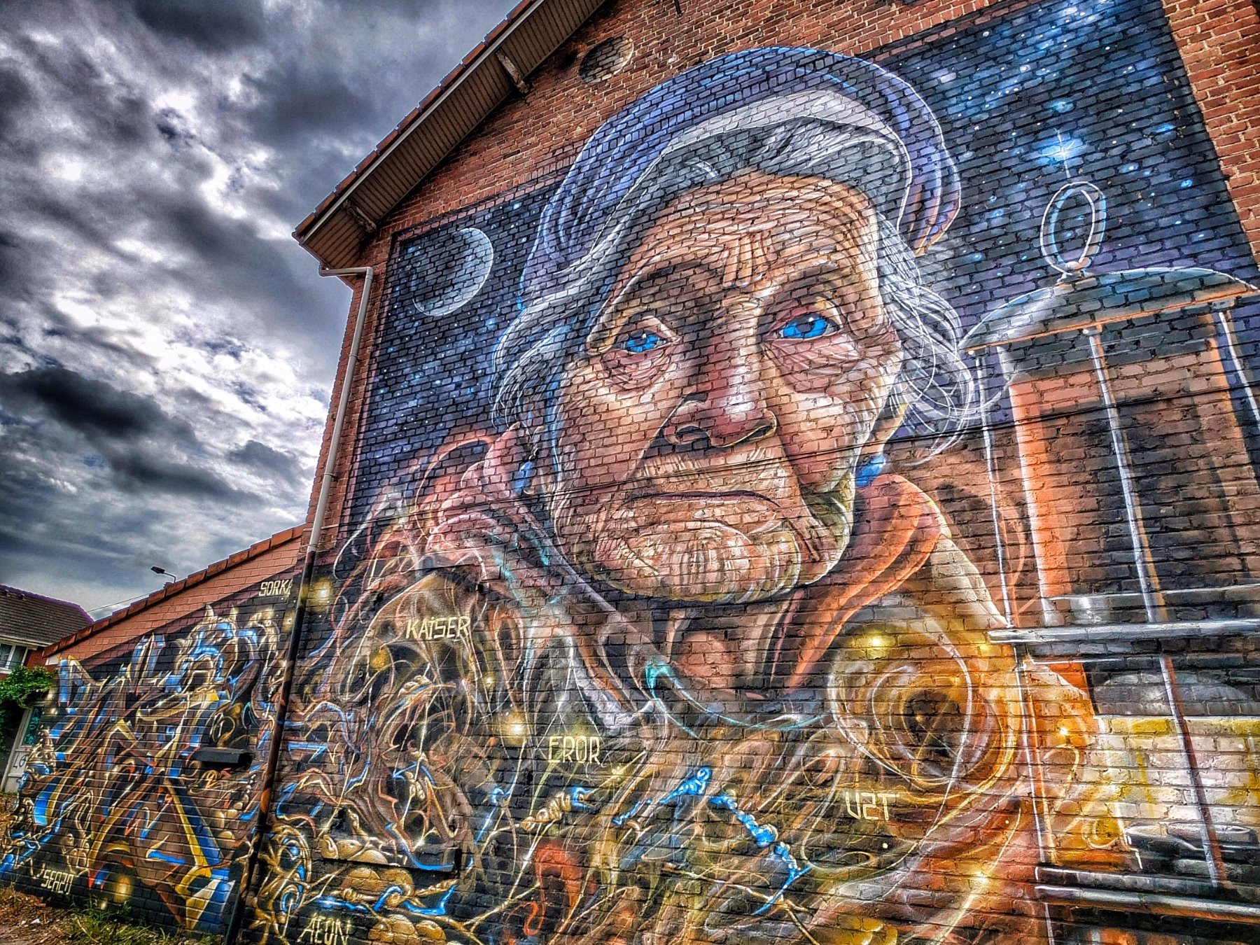 A mural of an old woman on a brick building.