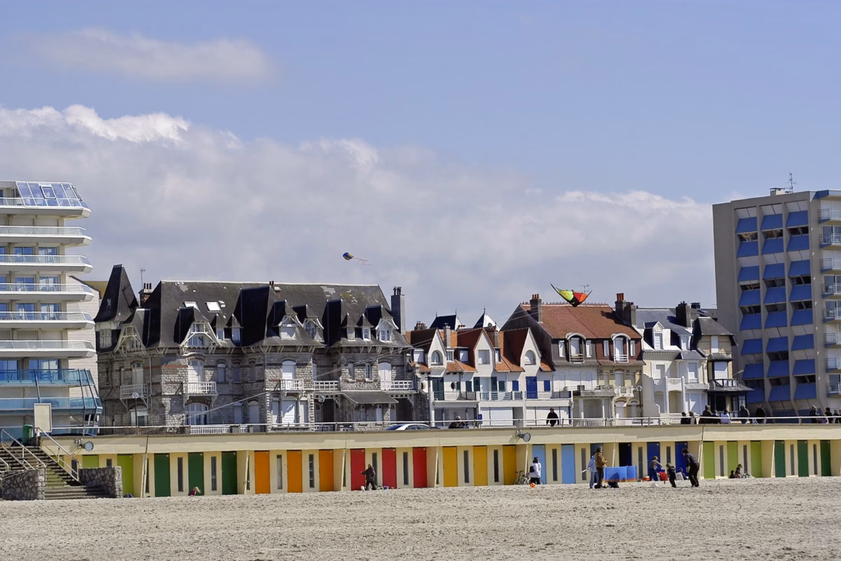 Plage avec cabines colorées et bâtiments.